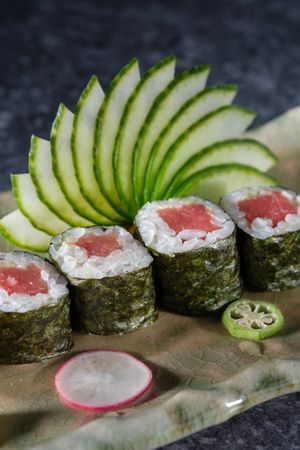 Delicious tuna sushi rolls served with fresh cucumber slices arranged on marble plate