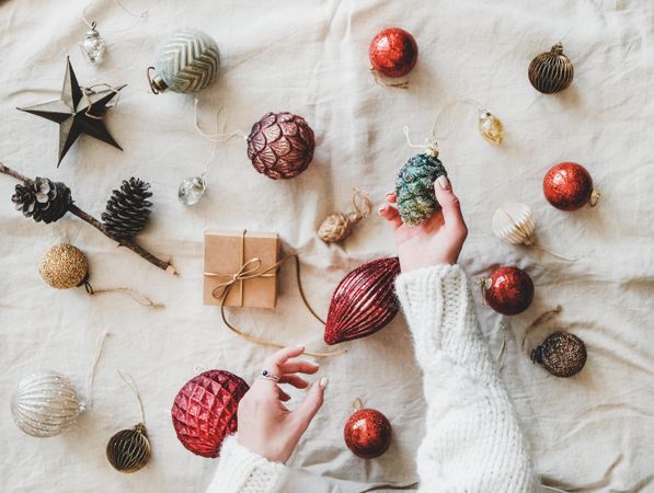 Flat-lay of holiday decoration, with hands holding pinecone top view