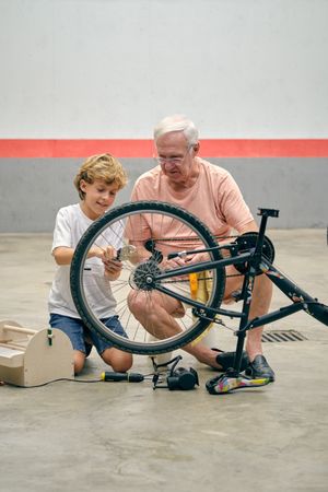 Grandson repairing bicycle with grandfather