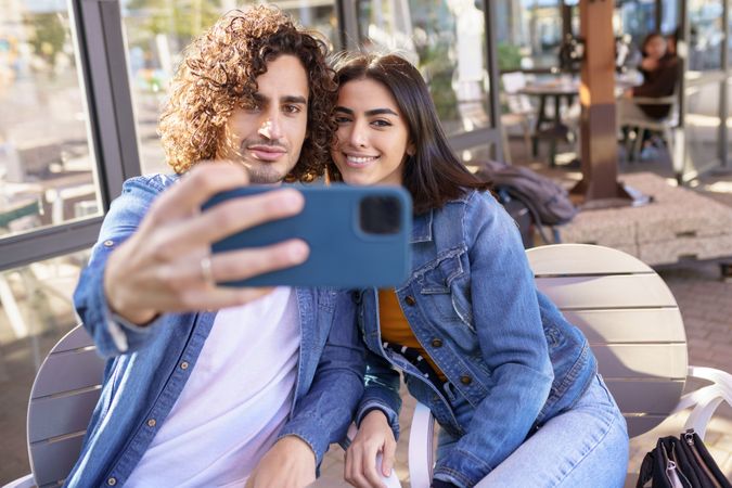 Man and woman taking selfie sitting down outside
