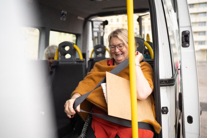 Happy woman on bus with art supplies