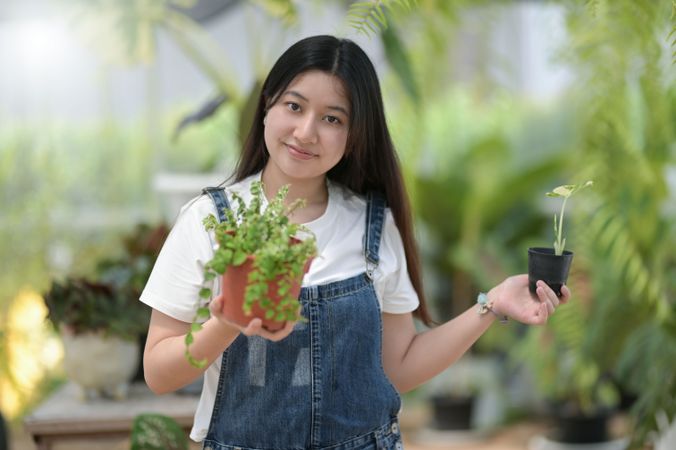 Asian female holding 2 pots of plants at work
