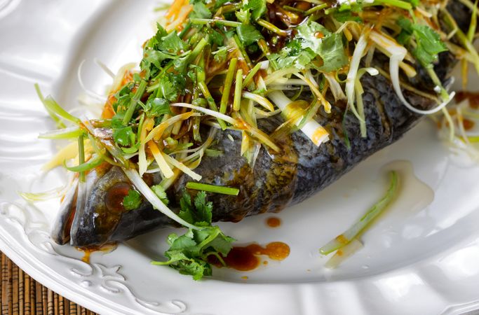 Steamed fish and garnishes on serving plate ready to eat