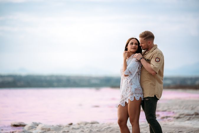 adorable couple standing on an amazing beach with pink water