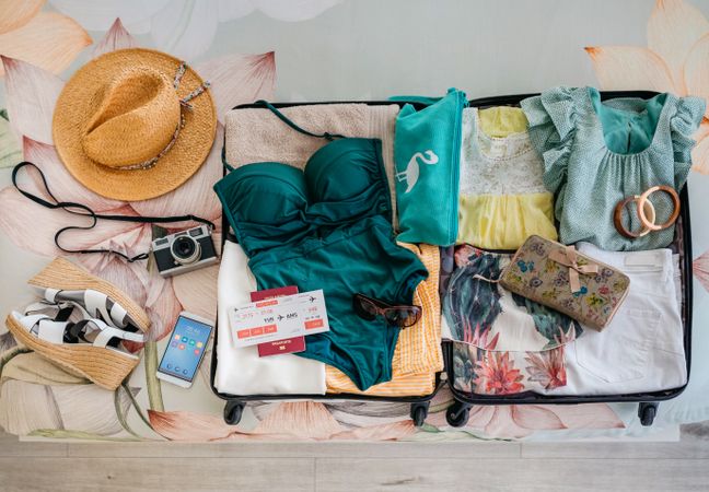 Open woman suitcase prepared for summer vacation