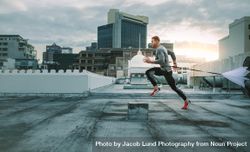 Side view of a fitness man running on rooftop using resistance parachute 4A7nY0
