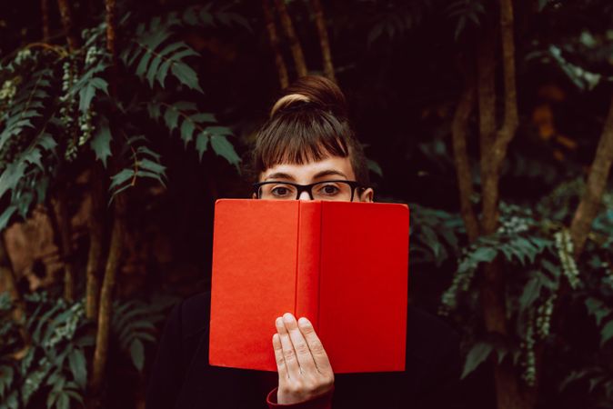Young woman reading book on bench in park