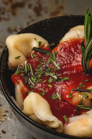 Plate of delicious ravioli with tomato sauce served on table