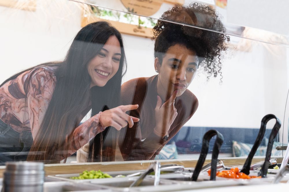 Multiethnic women choosing food in restaurant