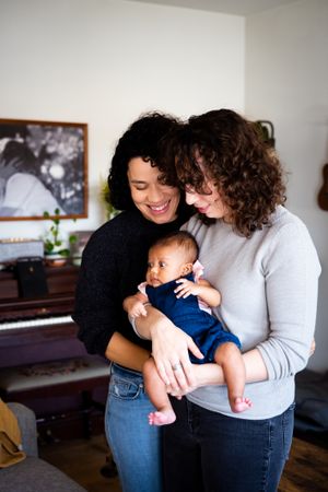 Loving couple looking down at their baby in the living room, vertical