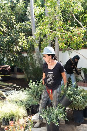 Female contractor wearing hard hat working outside in garden