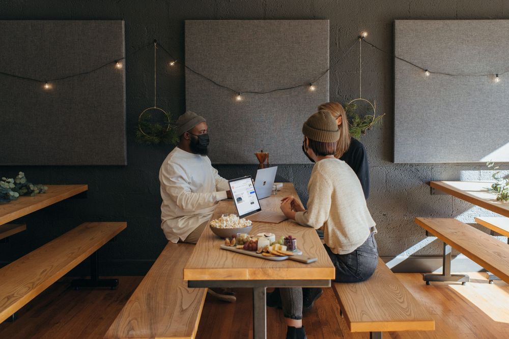 Group of people with facemasks working on their laptops in a restaurant