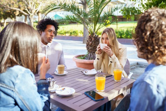 Group of friends having coffee and juice outside