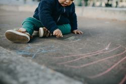 A toddler playing with chalk