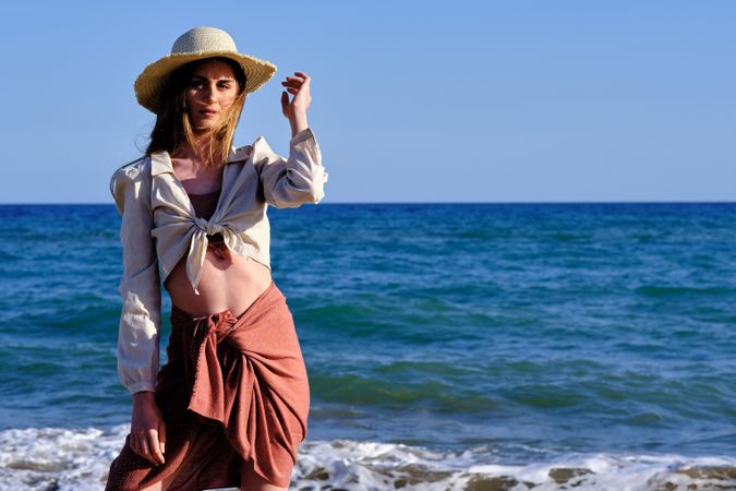 A fashion model with a hat at the beach before sunset