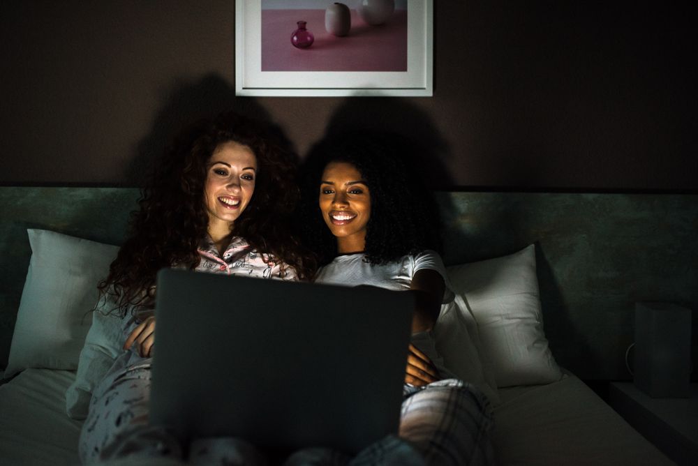 friends in bed entertained on their computer