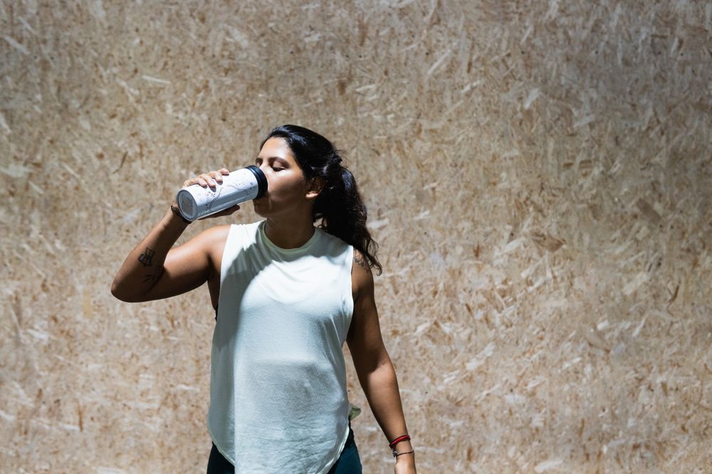 Hispanic woman drinking water in gym