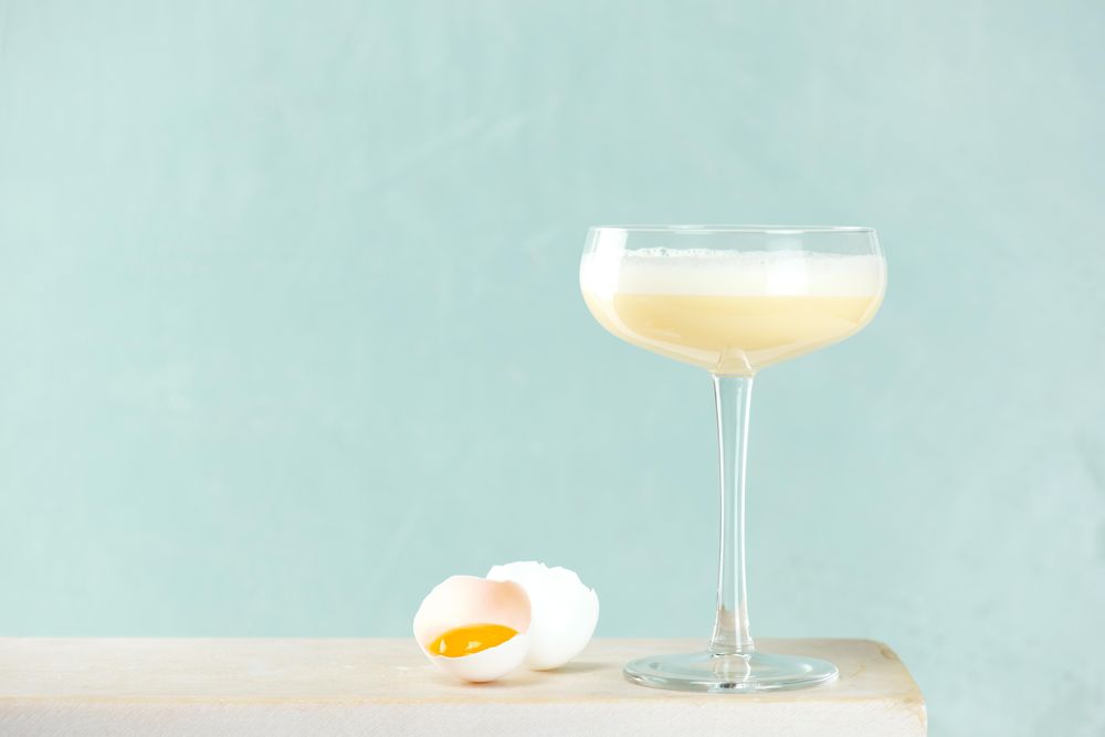 Eggnog in stem glassware with cracked egg.