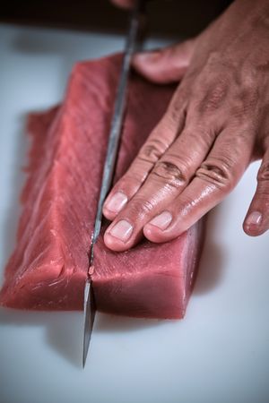 Male hands of a chef cutting a delicious loin of fresh bluefin t