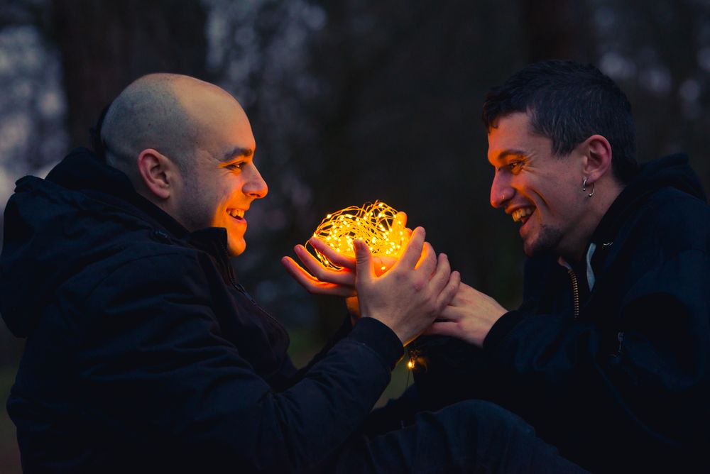 Men holding fairy lights near dog in forest at night