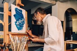 Older male artist signing his finished painting