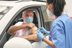 Crop medic preparing mature patient for vaccination in car