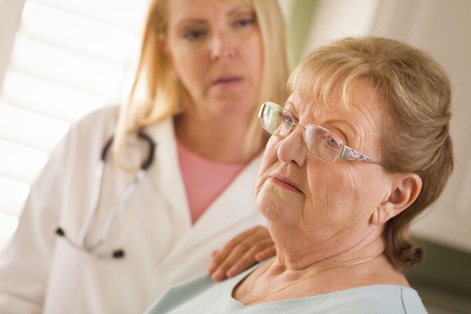 Older Adult Woman Being Consoled by Female Doctor or Nurse