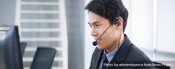 Side view of Asian man working at service desk talking on phone 5XeoK4
