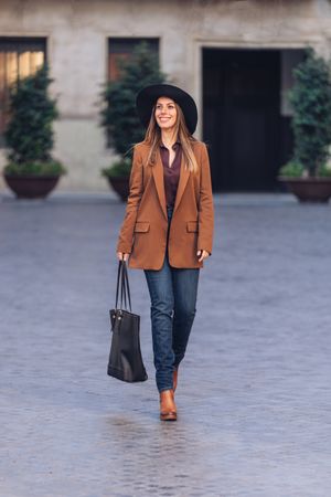 Gorgeous woman in fashionable outfit strolling on city street
