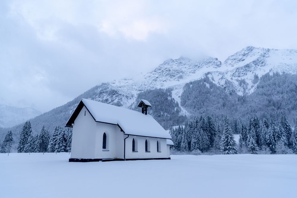 Snow-covered church minimalist in a winter scenery in the Bavarian Alps, Germany