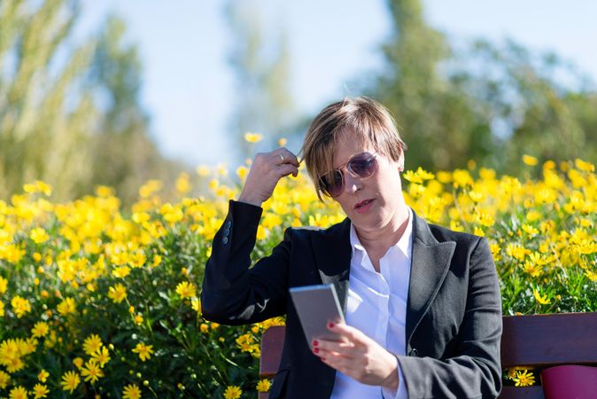 Professional woman checking phone in front of yellow flowers