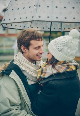 Couple facing each other under the umbrella on an autumn rainy day