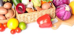 Wicker basket, wood board and vegetables isolated on blank background