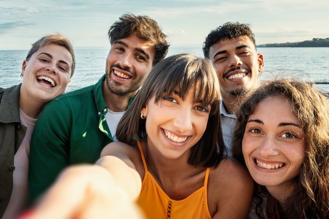 Diverse friends taking joyful selfie at seaside vacation