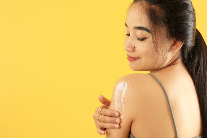 Asian Young Woman Applying Sunscreen Lotion on Her Upper Arm