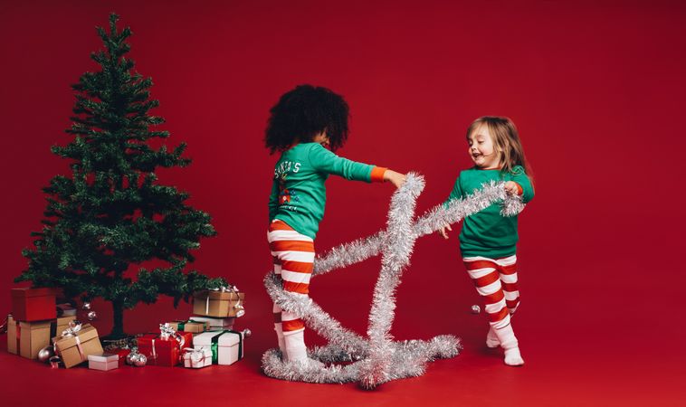 Kids playing with decorative ribbon near a Christmas tree