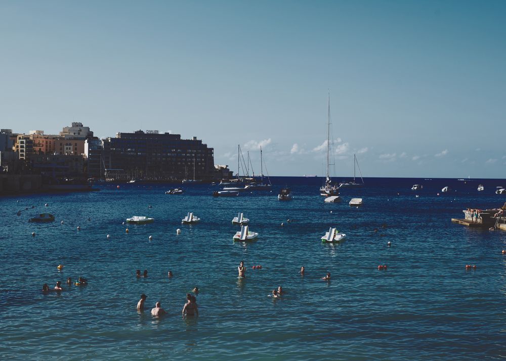 Swimmers, paddleboat and yachts in a harbor in the Mediterranean Sea