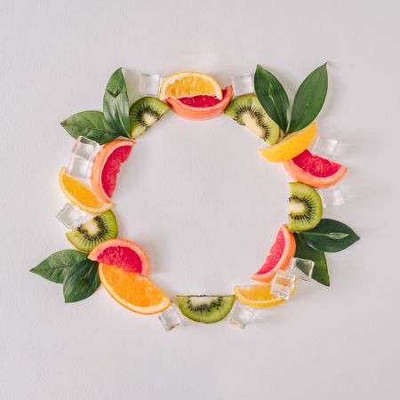 Round wreath with tropical citrus fruit slices, ice cubes and leaves