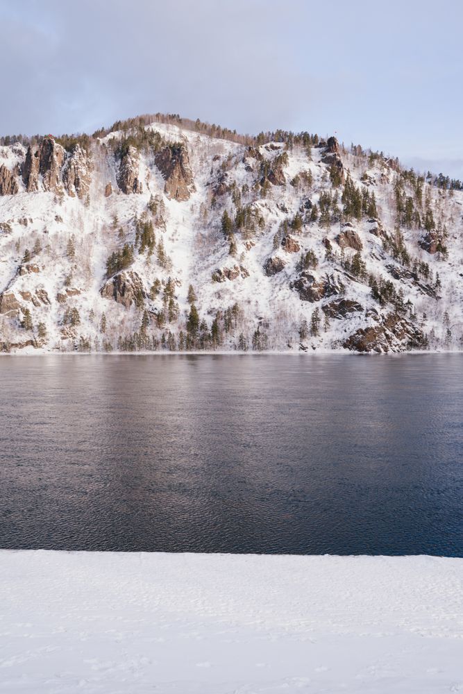 Wide Siberian river and snowy mountains