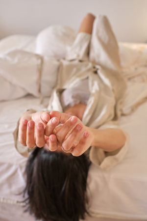 Anonymous female lying on bed and stretching in morning