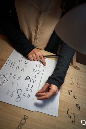 Faceless artisan with pendant drawing illustrations on paper