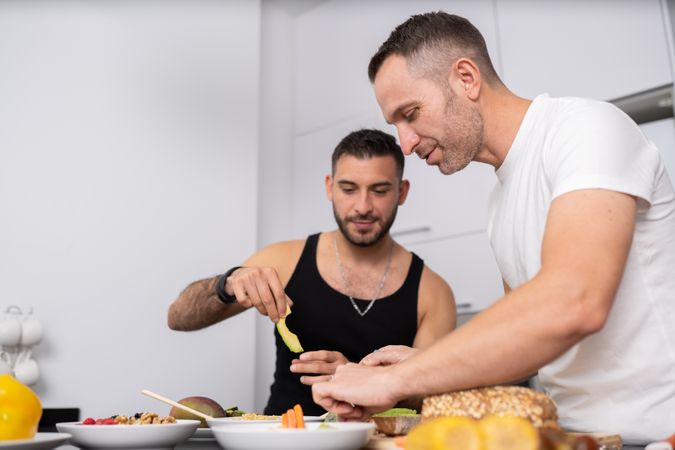 Male couple preparing avocados and bread for sandwich