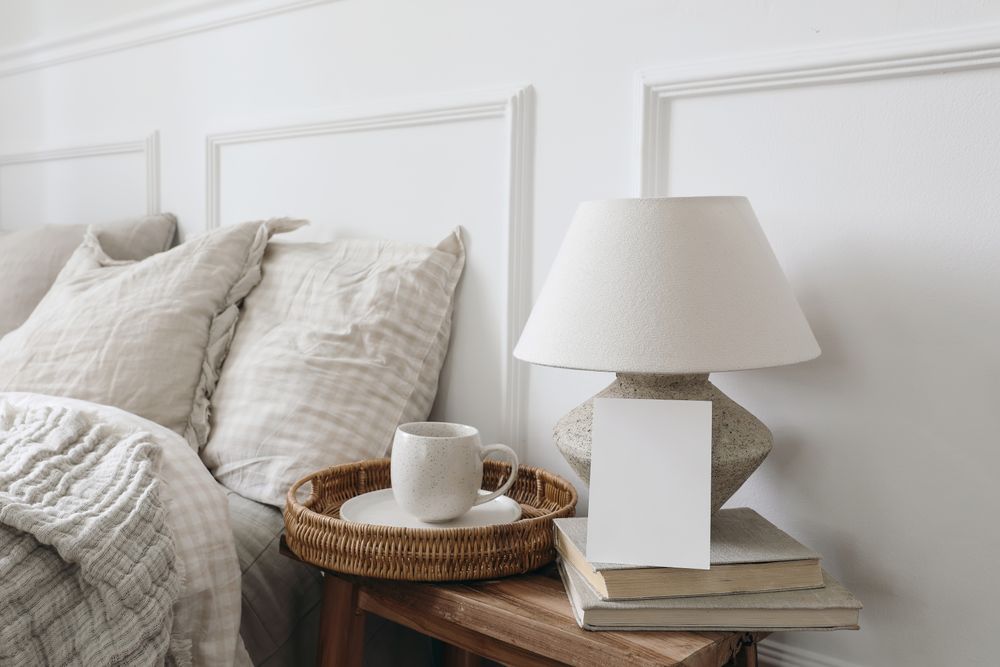 Bedside table with tray of coffee, lamp and mockup card
