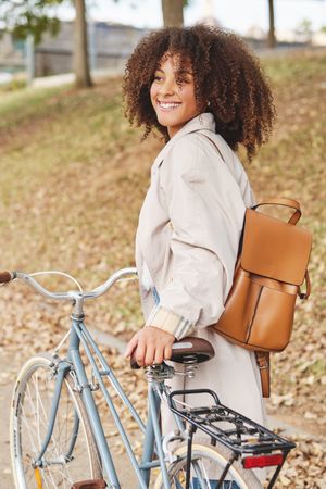 Smiling Black Latina woman with bicycle in autumn park