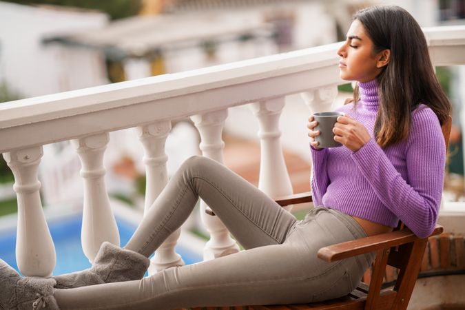 Female relaxing on outdoor patio with warm beverage