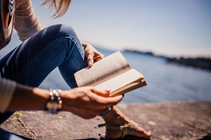 Close-up shot of woman reading a book near shoreline