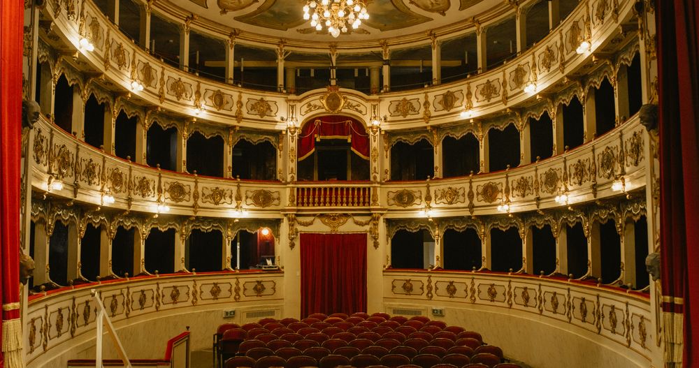 Wide shot of an Empty Elegant Classic Theatre with Red Velvet Chairs and Curtains.