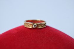 Man's diamond ring resting on red cushion
