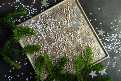Christmas card concept of pine branches and star confetti on silver tray