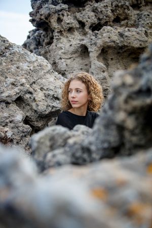 Young woman sitting between stones